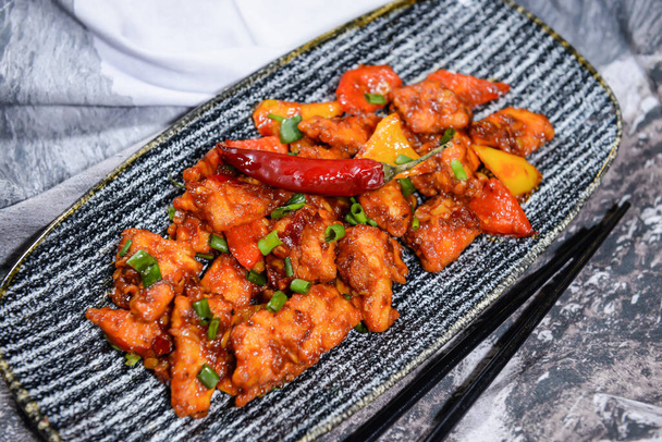 курица в стиле пекинского чили с весенним луком и помидорами подается в блюде, изолированном на пищевом столе - Фото, изображение