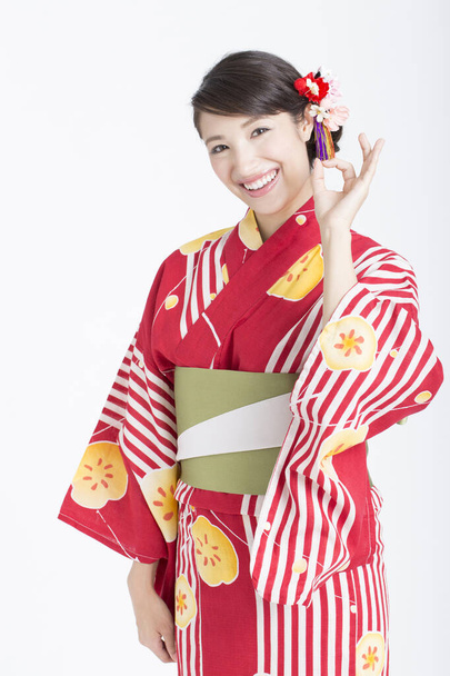 woman dressed in kimono looking at camera and showing ok sign - Fotografie, Obrázek
