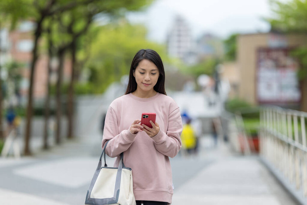 女性は街でスマートフォンを使う - 写真・画像