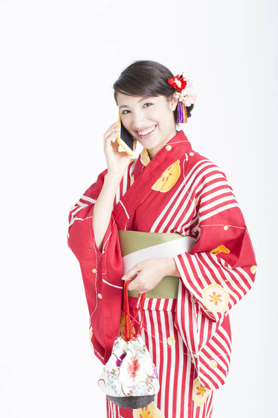 smiling Asian woman wearing kimono with mobile phone - 写真・画像