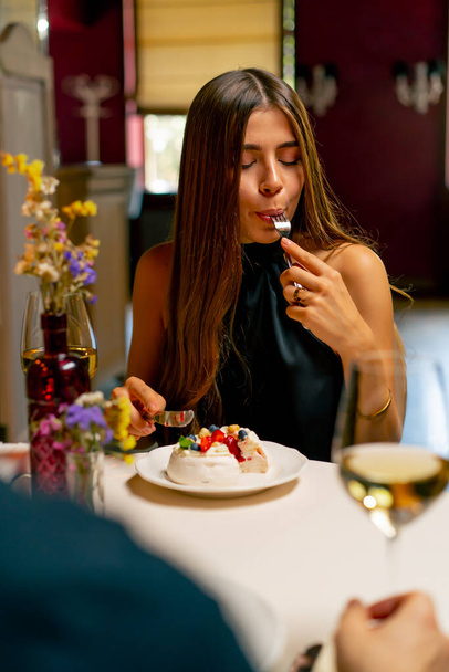 Close-up of a cute young girl eating a delicious dessert cake during a date at Italian restaurant - Photo, Image
