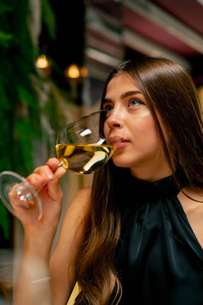 Close-up cute młoda dziewczyna pije drogie pyszne wino podczas randki we włoskiej restauracji - Zdjęcie, obraz