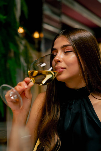 Κοντινό πλάνο ενός χαριτωμένου νεαρού κοριτσιού πίνοντας ακριβό νόστιμο κρασί κατά τη διάρκεια ενός ραντεβού στο ιταλικό εστιατόριο - Φωτογραφία, εικόνα