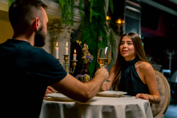 Jeune couple mec et fille assis dans un restaurant italien doucement bavarder et boire du vin tout en date - Photo, image