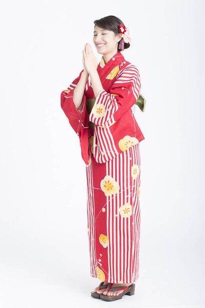 the young beautiful asian woman in traditional clothing standing and praying on studio background - Photo, image
