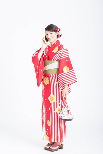 smiling Asian woman in traditional dress with smartphone - 写真・画像
