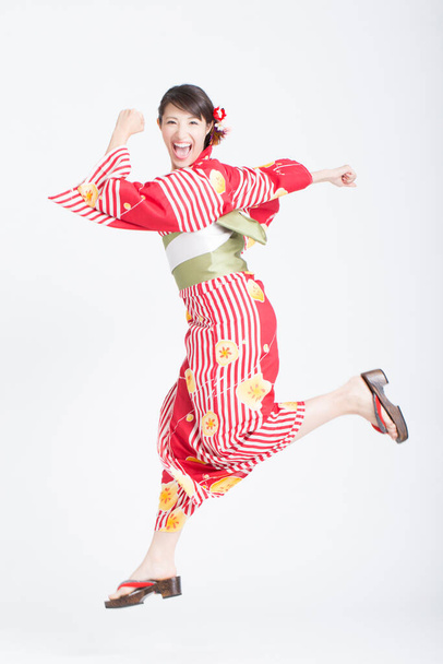 Asian woman wearing traditional japanese kimono running on white studio background - Foto, Imagen