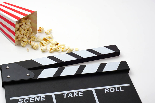 Klapperboard lub film łupek czarny kolor z popcornem na białym tle. Przemysł kinowy, produkcja wideo i koncepcja filmu. - Zdjęcie, obraz