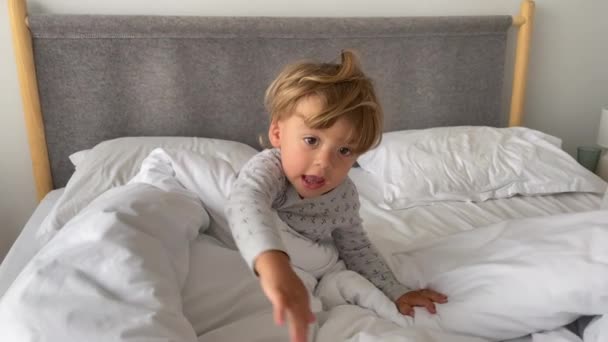 Cute baby boy in bed in the morning. Infant caucasian blond boy waking up - Felvétel, videó