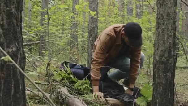 Tiro completo de jovem turista Biracial do sexo masculino que estabelece para dormir na cama auto-feita na floresta - Filmagem, Vídeo