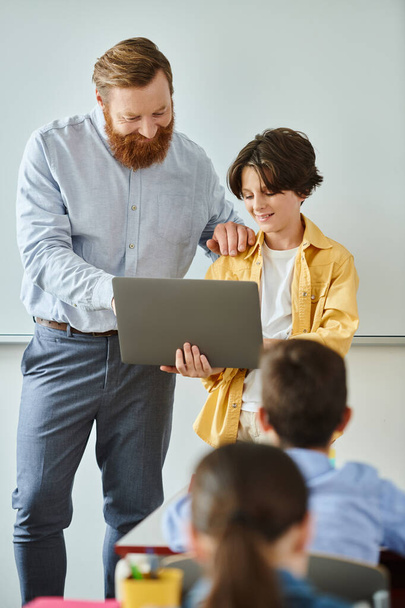 Um homem e um menino estão juntos na frente de um computador portátil, trabalhando em colaboração em uma tarefa. - Foto, Imagem