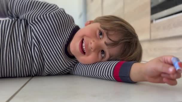 Happy child laying on floor smiling. Closeup kid boy. childhood lifestyle of joyful kid - Materiał filmowy, wideo