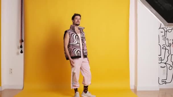 Video con la cámara acercándose a un hombre gay posando en un estudio fotográfico con ropa moderna rosa - Metraje, vídeo