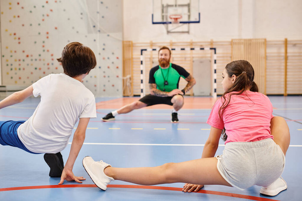 Un groupe diversifié d'enfants s'engagent dans une séance d'entraînement intense dans la salle de gym de l'école - Photo, image