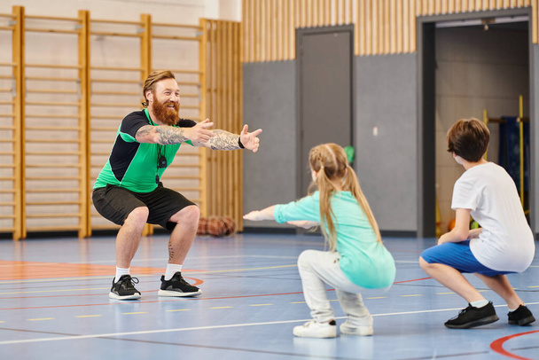 Un grupo de personas participan con entusiasmo en una clase de educación física en un gimnasio escolar - Foto, imagen