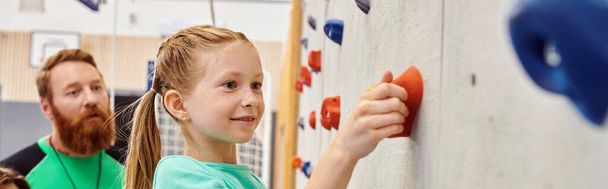 A man and a little girl stand side by side, climbing wall - Photo, Image