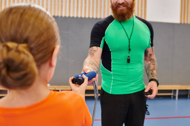 Un hombre vistiendo una camisa verde está jugando alegremente un juego con una niña - Foto, Imagen