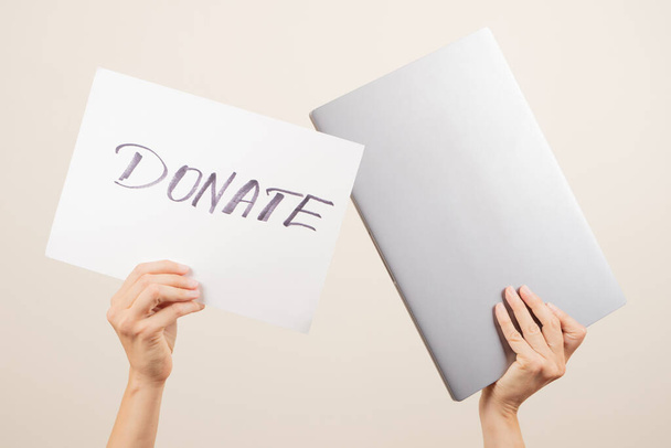 Spenden für wohltätige Zwecke. Ehrenamtliche Hände halten Laptop und Papiertafel mit Wort Spenden. - Foto, Bild