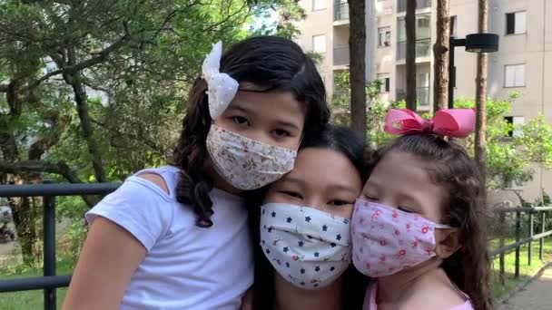 パンデミックの流行の間、公園の外で顔マスクを身に着けている家族。3人だ。子供と母親. - 映像、動画