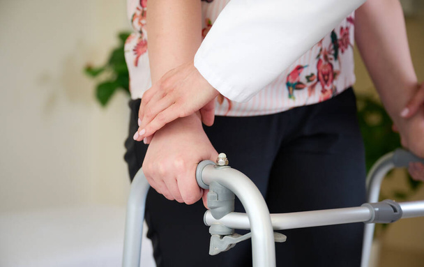 Doctor holding a patient's hand, helping to move. Walkers for adults. Rehabilitation after stroke. Physiotherapy in the hospital. Close up view of the hands. - Photo, Image