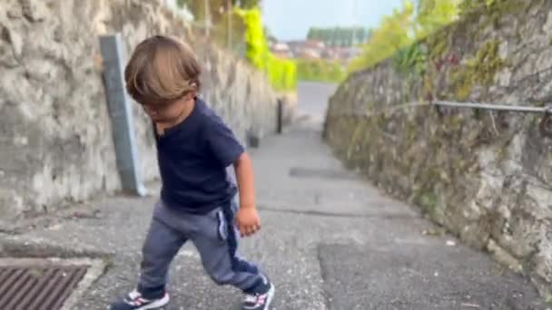 One upset little boy going uphill. Effortful tired child climbing up on road. - Video, Çekim