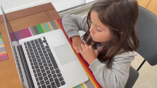 Femmina bambino di fronte computer portatile compuer. Ragazzina guardando i media di intrattenimento sulla tecnologia moderna a casa balcone appartamento - Filmati, video