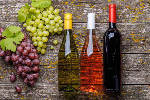 Weinflaschen und Trauben auf einem Holztisch. Flache Lage - Foto, Bild