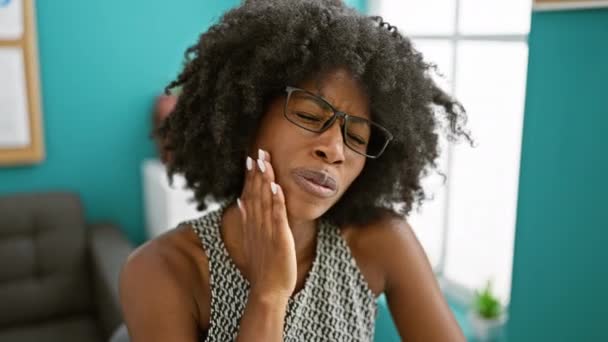 Afrikai-amerikai női üzletember szenved fogfájás az irodában - Felvétel, videó
