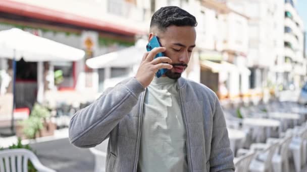 Joven hombre hispano hablando por teléfono mirando la hora en la calle - Metraje, vídeo