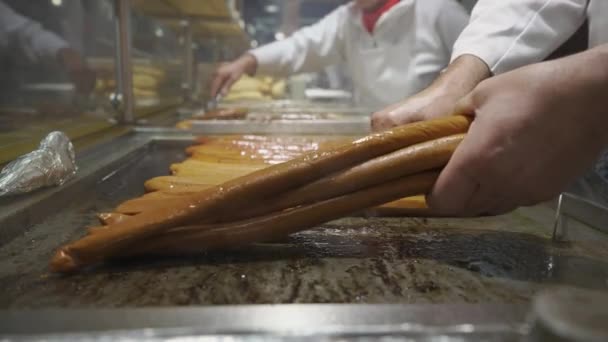 Κοντινό πλάνο του μάγειρες χέρι τηγάνισμα Βαυαρικά λουκάνικα το βράδυ σε ένα πανηγύρι στη Γερμανία, Μόναχο. Μπράτγουερστ σε ψησταριά. Φαγητό του δρόμου. Υπαίθρια κουζίνα στην τοπική αγορά του παραδοσιακού φεστιβάλ.  - Πλάνα, βίντεο
