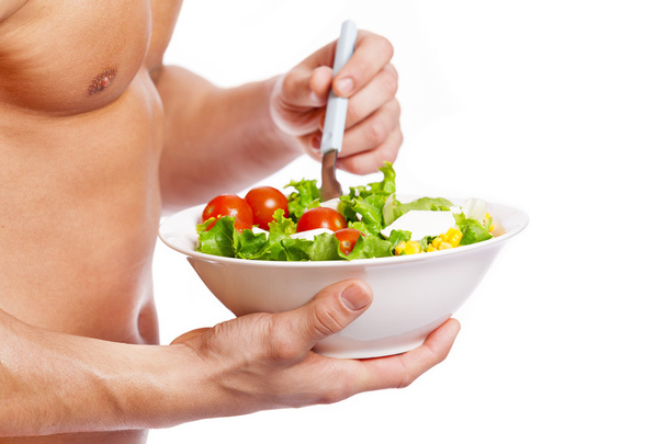 Fit man holding a bowl of fresh salad - Photo, image
