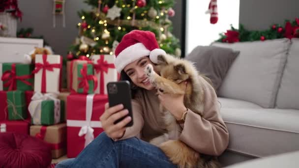 Молодая латиноамериканка с собакой на видео-звонке празднует Рождество дома - Кадры, видео