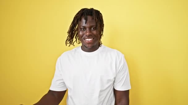 Afrikaanse amerikaanse man glimlachen zelfverzekerd dansen over geïsoleerde gele achtergrond - Video