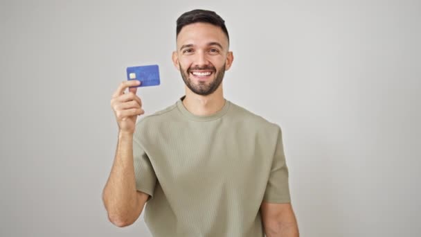 Młody Hiszpan uśmiecha się pewnie trzymając kartę kredytową i dolary na białym tle - Materiał filmowy, wideo