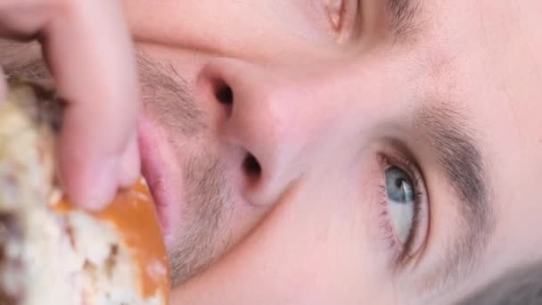 Egy közeli kép üzletemberről, aki hamburgert eszik ebédszünetben. Ártalmas utcai kaja. Függőleges videó. - Felvétel, videó