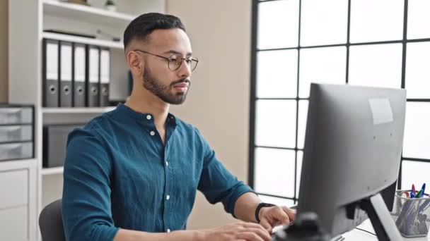 Молодой латиноамериканец, бизнесмен, использующий компьютер, смотрит на время в офисе - Кадры, видео