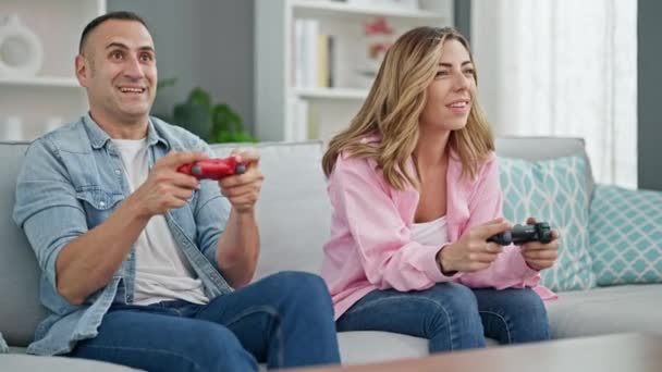 Hombre y mujer pareja jugando videojuegos celebrando en casa - Metraje, vídeo
