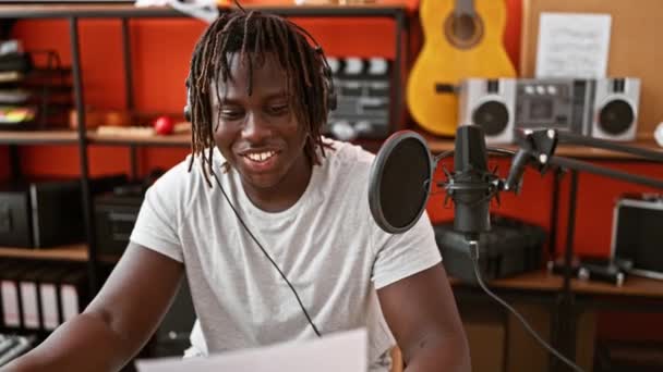 Africano americano hombre músico sonriendo confiado cantando canción en estudio de música - Imágenes, Vídeo