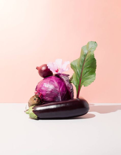Stilleven met aubergine, kalebas, paarse kool, biet, bietenblad, rode ui en hibiscus bloem. Creatief groenteconcept op helling achtergrond - Foto, afbeelding