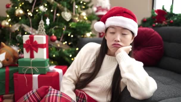 Fiatal kínai nő ül a padlón karácsonyfa komoly kifejezés otthon - Felvétel, videó