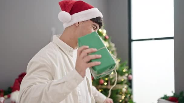 Giovane uomo ispanico che tiene il regalo di Natale ballando a casa - Filmati, video