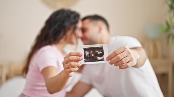 Mies ja nainen pari istuu sängyllä pitäen vauvan ultraääntä makuuhuoneessa - Materiaali, video