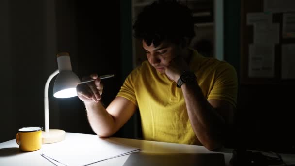Jeune homme d'affaires latino-américain lisant un document avec un visage sérieux au bureau - Séquence, vidéo