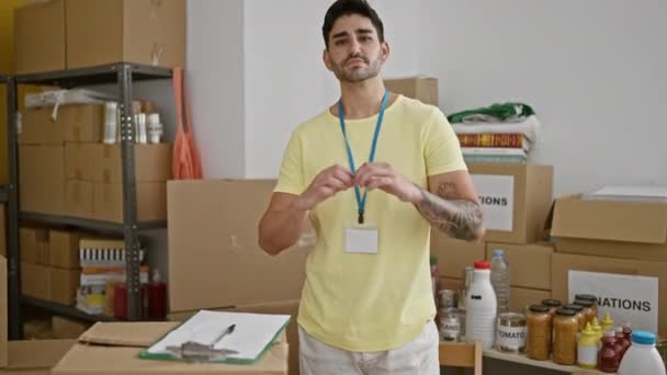 De jonge Spaanse man glimlacht vol zelfvertrouwen en doet een hartengebaar in een liefdadigheidscentrum. - Video