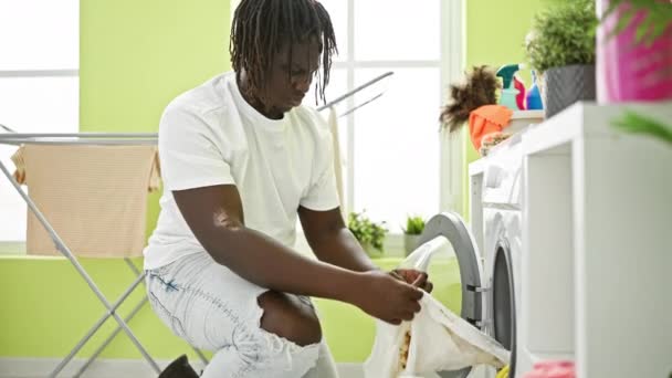 Африканський американець миє одяг, тримає брудну сорочку в пральні - Кадри, відео