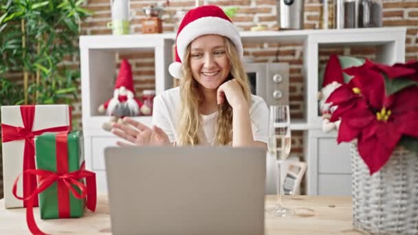 Fiatal szőke nő ünnepli karácsony videohívás ivás pezsgő ebédlőben - Felvétel, videó
