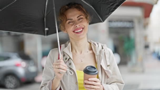 Fiatal nő kezében esernyő és kávé sokat nevet az utcán - Felvétel, videó