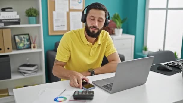Молодий іспаномовний чоловік бізнесмен слухає музику, танцює в офісі - Кадри, відео