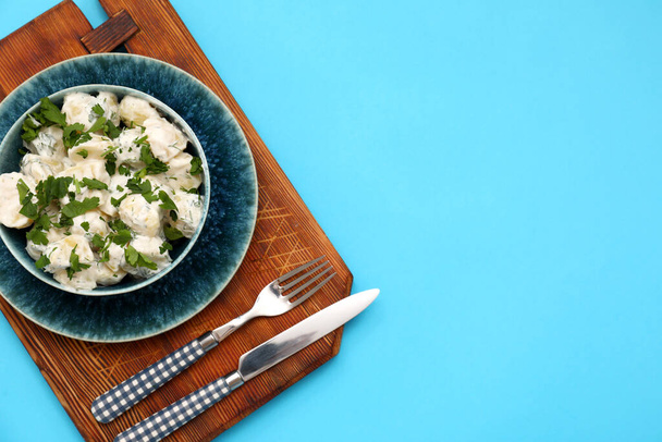 Bowl of tasty Potato Salad with greens on blue background - Photo, Image