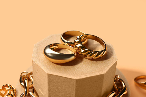 Podi decorativi con anello d'oro e bracciale su sfondo arancione - Foto, immagini
